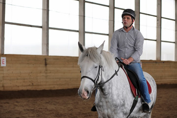 People on a horse training in a wooden arena