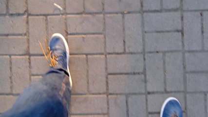 The legs of a drunken man walking down the sidewalk. The concept of alcoholism and drug addiction