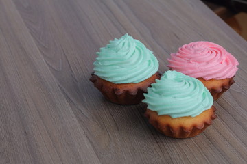 Three cream cakes of different colors. Stand by a triangle.