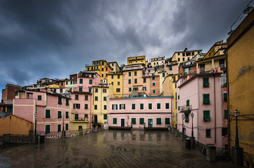 Naklejka na ściany i meble View of a square in Manarola after a rain with dark heavy sky. Manarola is one of the five towns of Cinque Terra located on the coast of Ligurian Sea in Italy.