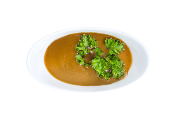 Brown sauce in a small plate with parcley isolated on white. Top view. With clipping path