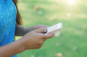 hipster woman using mobile phone touching screen at outdoor in green park background, hands typing smart phone texting messaging lifestyle working app device technology internet social online concept.