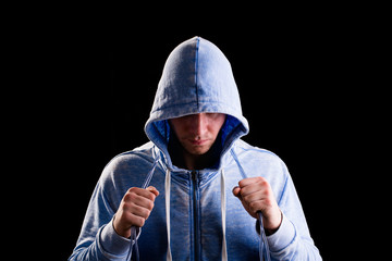 Athlete in the hood holding a jump rope. Jumping rope. Athlete in hood on a black background. Drops...