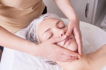 Fototapeta na wymiar Closeup of young woman receiving face massage from massage therapist.