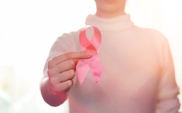 The red ribbon of the girl. The girl is holding a red ribbon. Health concept and red ribbon. Breast cancer.