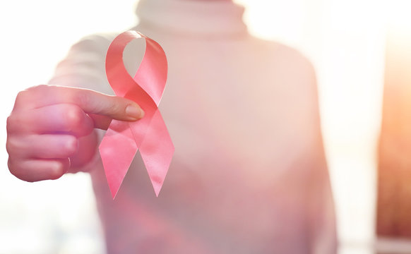 The red ribbon of the girl. The girl is holding a red ribbon. Health concept and red ribbon. Breast cancer.