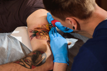 Master working tattooing in tattoo studio./Professional tattooist works in studio.