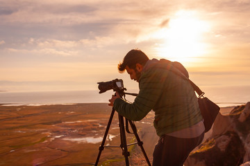 Men photographer on top of mountain at sunset background 