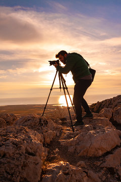 Men photographer on top of mountain at sunset background 