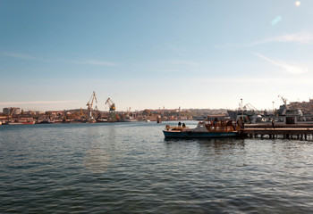 Fototapeta na wymiar SEBASTOPOL, RUSSIA - NOVEMBER 4,2018: view of the port with cranes and fishermen fishing on a boat
