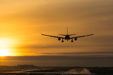 Fototapeta na wymiar Airplane landing to airport runway in sunset