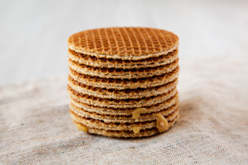 Stack of homemade Dutch stroopwafels with honey-caramel filling on cloth, side view. Close-up.