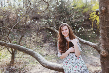 beautiful young woman reading a retro book in a garden with blooming trees