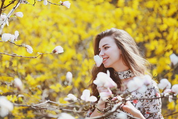 Naklejka premium beautiful young woman sniffing a flowering tree in the garden