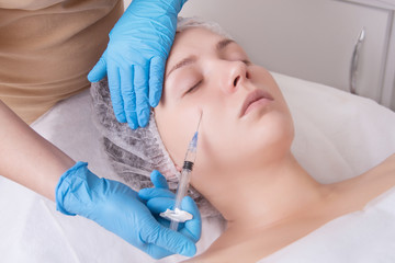 Hands of cosmetologist are close-ups that inject hyaluronic acid.