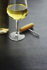 Transparent bottle of white dry wine on the table. White wine glass on a wooden background.