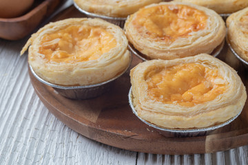close up of egg tarts on wooden plate