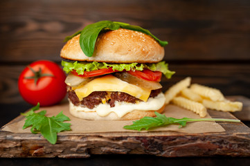 Delicious homemade hamburger with beef, salad, cheese, cucumber and french fries chalkboard on wood background