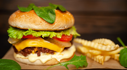  Delicious homemade hamburger made of beef, salad, cheese, cucumber and french fries on a wood background