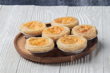 close up of egg tarts on wooden plate
