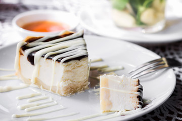 Cheesecake with a white and dark chocolate on a plate in a cafe. Healthy sweet dessert, mousse cake