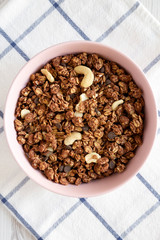 Homemade chocolate granola with nuts in a pink bowl, top view. From above, overhead. Close-up.