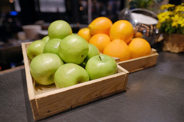 Orange and apple in a wooden crate.