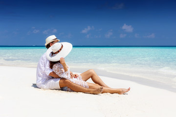 Romantisches Paar sitzt am tropischen Strand und genießt seinen Urlaub auf den Malediven