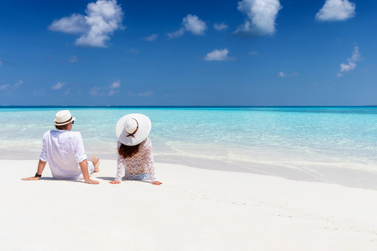 Verliebtes Paar sitzt am tropischen Strand mit türkisem Meer und genießt den Urlaub 
