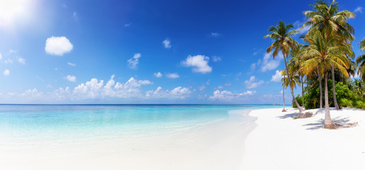 Weites Panorama eines tropischen Strandes mit türkisem Meer, Palmen und feinem Sand auf den Malediven