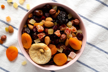 Dried fruits and nuts in a pink bowl, overhead view. Flat lay, from above, top view. Close-up.