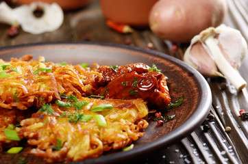 Closeup view at Homemade tasty potato pancakes in clay dish with sun-dried tomatoes