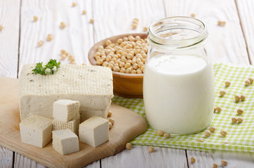 Non-dairy alternatives Soy milk or yogurt in mason jar and tofu on white wooden table with soybeans in bowl aside