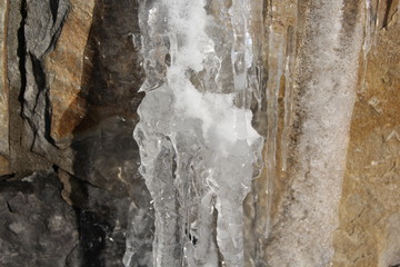 Icicles hanging on a ledge with rocky bacground