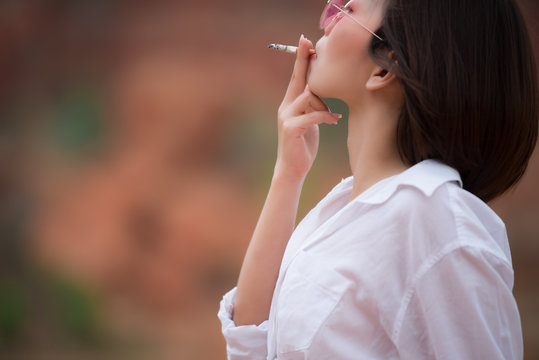 Portrait of asian beautiful woman wear white shirt and short denim,Thailand people,Pose for take a picture,Sexy woman,She is smoking