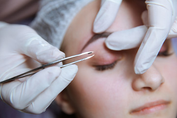 Naklejka premium Process of making eyebrows. Pretty woman with closed eyes on the procedure