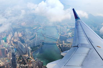 Airplane flies over Hong Kong. Passenger jet plane flying above urban scene. Hongkong flight. Asian...