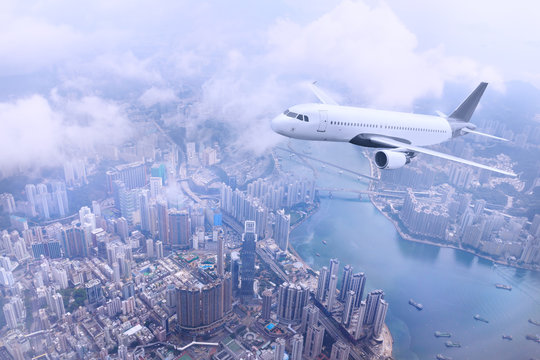 Passenger Plane Fly To Hong Kong Island. Aerial View At Cityscape. Airplane Over Urban Skyline. Concept Of Travel And Air Transportation.