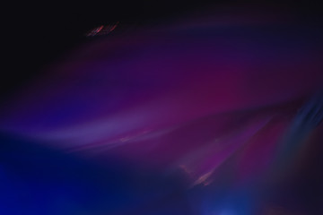 Blurred neon multicolor abstract lines on dark background. Defocused lens flare glow effect.