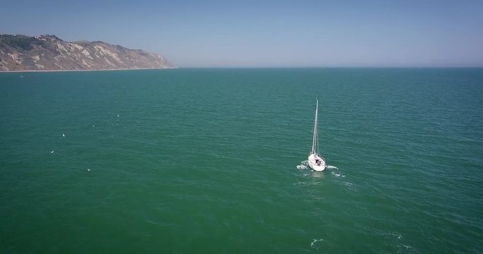 Vista aerea di una Barca a vela che solca il mare nei pressi di Pesaro nella regione Marche in Italia. Si nota la falesia del parco San Bartolo a picco sul mare 