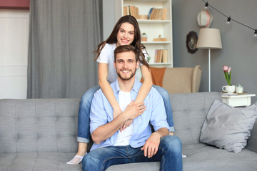 Beautiful woman with boyfriend spending quality time together on sofa at home in the living room.