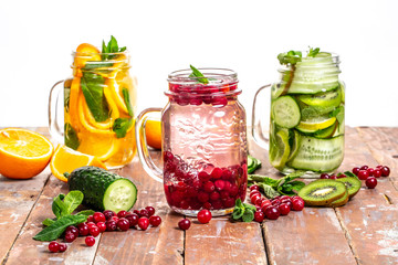 Three types of detox water with fruit in glasses on a white background. space for text