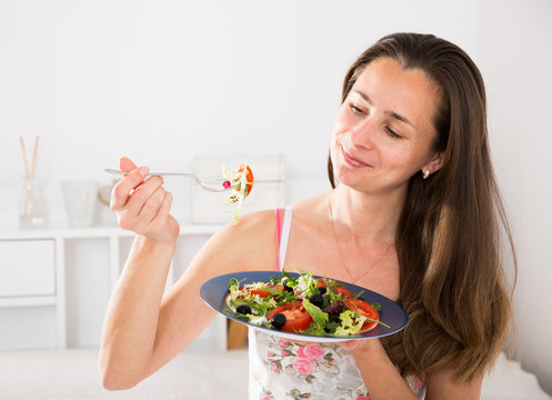 Woman eating an appetizing salad in bed