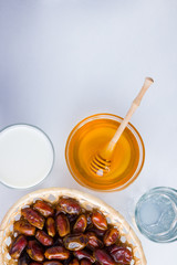 Dried dates, milk and honey on white background. Holy month of Ramadan, concept. Righteous Muslim lifestyle. Starvation. Dates in wooden basket and honey. Vegetarian food. Copy space