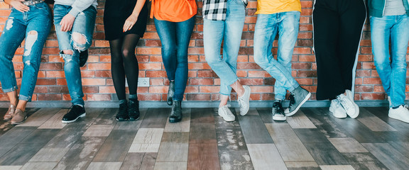 People diversity. Cropped shot of men women legs in jeans. Group standing leaning against brick...