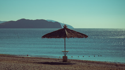 Straw beach umbrella stands on the sea beach