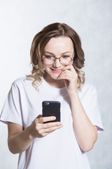 Perplexed and worried, a beautiful young woman is holding a smartphone, stares with surprised expression.