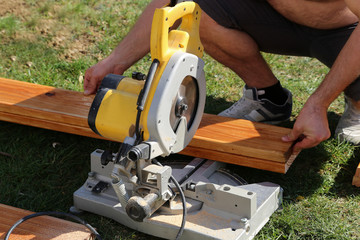 A worker saw wood with a chop saw