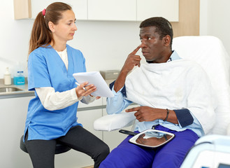 Cosmetician with papers talking to man before procedure in medical esthetic office