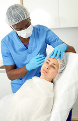 Doctor in mask is doing injection to woman patient in skin of face in estetic clinic